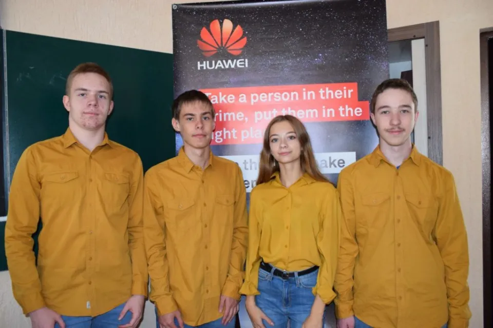 Four members of Ukraine’s team in matching mustard shirts standing in front of a banner
