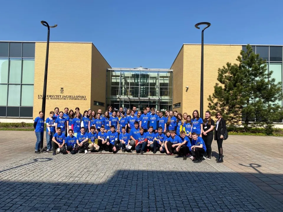 A large group of UJGOI contestants in blue T-shirts in front of the Jagiellonian University’s Faculty of Mathematics and Computer Science